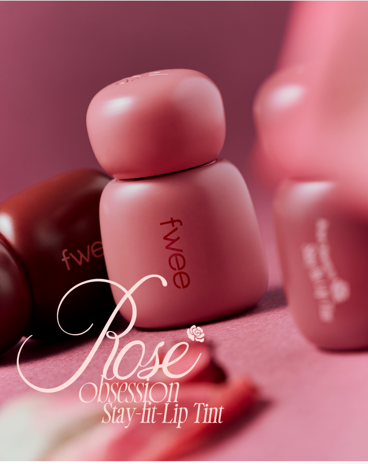 로즈 톤 배경 위에 놓인 fwee 로즈 옵세션 스테이 핏 립 틴트 패키지 제품 이미지